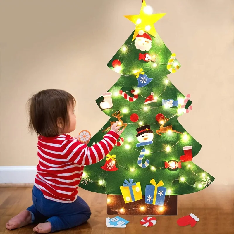 Criança decorando uma árvore de Natal de feltro na parede